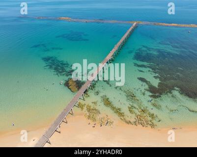 Aus der Vogelperspektive auf einen langen Küstensteg, der zu einem felsigen Riff in einer flachen Bucht bei Port Noarlunga in South Australia führt Stockfoto