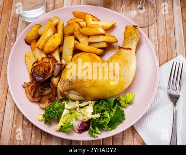 Hähnchenschenkel mit gebackenen Kartoffeln, braunen Zwiebeln und frischem Salat Stockfoto