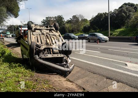 Beschädigtes Fahrzeug nach einer Kollision, die kopfüber auf der Straße lag. Geschäftige Stadtstraße mit Auto, das tagsüber überfahren wurde. Autounfall Stockfoto