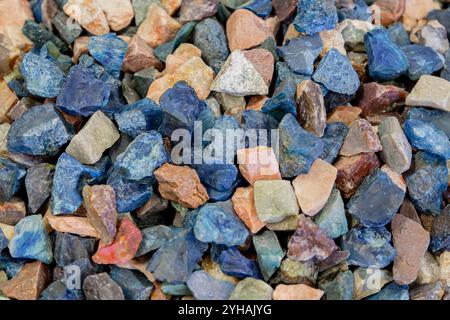 Hintergrund mit einem Stapel von bunten Edelsteinen mit natürlichem Muster für eine schöne Textur. Farbenfroher Steinhintergrund. Sammlung verschiedener roher Edelsteine in verschiedenen Farben und Formen, Nahaufnahme Stockfoto