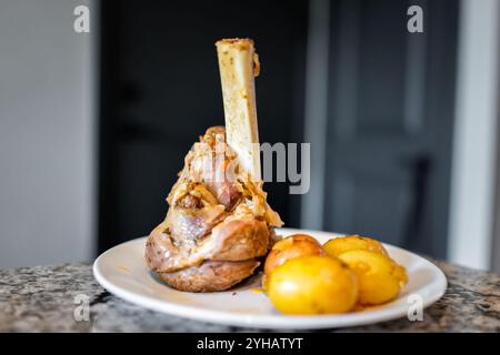 Gebratene Lammkeule Makros von braunem Fleisch mit Kartoffeln auf weißem Teller Nahaufnahme Stockfoto