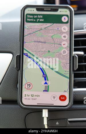 London, Großbritannien – 19. September 2024: Das iPhone Smartphone auf dem Armaturenbrett zeigt eine Wegbeschreibung in England Großbritannien an. Stockfoto