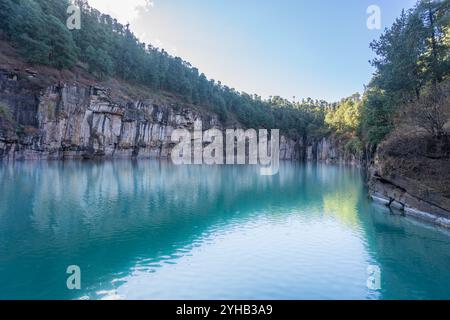 Das Foto zeigt den atemberaubenden Lac Tritriva, einen vulkanischen See mit leuchtendem blauem Wasser, umgeben von vertikalen Gneisklippen mit markantem schwarzem und Stockfoto