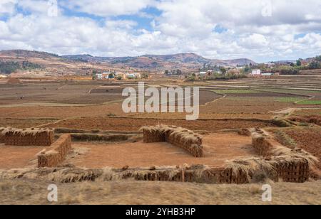 Traditionelles Lehmziegelwerk mit gestapelten Ziegeln im Vordergrund mit Blick auf terrassiertes Ackerland. Sanfte Hügel mit ländlichen Häusern und Flecken Stockfoto