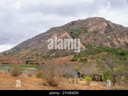 Dramatische Sandsteinklippen erheben sich über trockenem Savannengras unter hellblauem Himmel mit verstreuten weißen Wolken. Jurassische geologische Formationen A Stockfoto