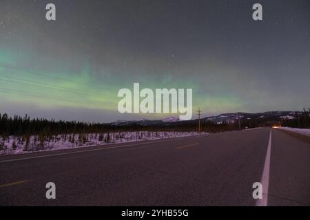 Nächtlicher Blick auf den Alaska Highway im Norden Kanadas, Yukon Territory mit einigen aurora Borealis, Nordlichtern und Stadtlicht. Stockfoto