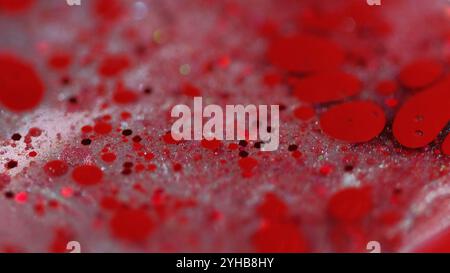 Funkelnde Blasen. Glitzer Farbe Mischung. Unschärfe rote Farbe glänzende Pailletten Partikel Tinte Tropfen transparente Gelflüssigkeit verschütten abstrakten Kunsthintergrund mit Bokeh Lichtern. Stockfoto
