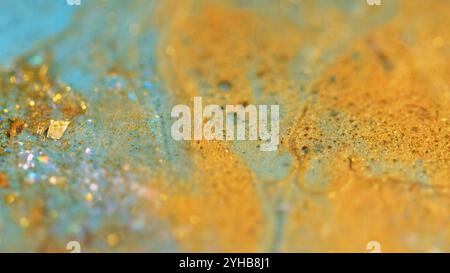 Glänzende Ölblasen. Glänzende Tinte. Unschärfe blau goldene Farbe metallische Pailletten Partikel Glanz flüssige Farbe Mischung abstrakte Kunst Hintergrund mit Bokeh Lichter. Stockfoto