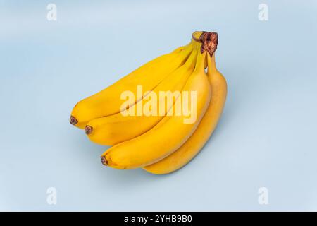 Süße Bananen auf blauem Holztisch auf weißem Hintergrund. Blick von oben Stockfoto