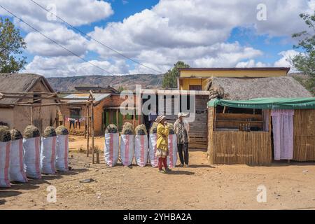 Isalo National Park, Madagaskar - 30. August 2024: Dorfbewohner stehen vor traditionellen Häusern mit Säcken Kohle zum Verkauf. Ländliche Szene mit dem Stockfoto