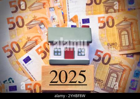 Miniaturhaus und Münzstapel. Das Konzept, Geld zu sparen für Haus, Immobilieninvestitionen, Haushypotheken, Immobilien im Jahr 2025 Stockfoto