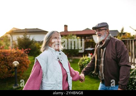 Porträt eines schönen Seniorenpaares draußen in einem Herbstgarten. Ältere Ehemann und Ehefrau haben Spaß miteinander, lachen. Stockfoto