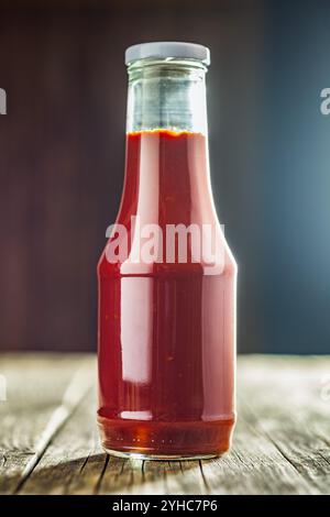 Glasflasche Ketchup auf einem Holztisch. Stockfoto