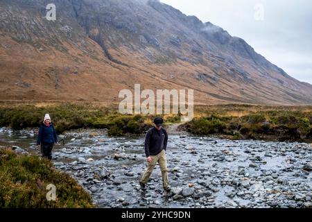 Menschen überqueren Einen Fluss während einer Wanderung durch die Cuillin Hiills/Mountains auf dem Sligachan zum Elgol Walk, Isle of Skye, Schottland, Großbritannien. Stockfoto