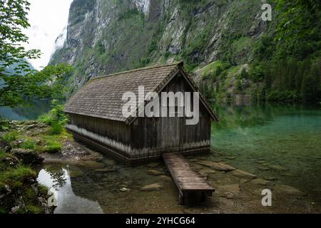 Hölzernes Bootshaus am kristallklaren Obersee im Nationalpark Berchtesgaden. Umgeben von zerklüfteten Klippen und üppigem Grün Stockfoto