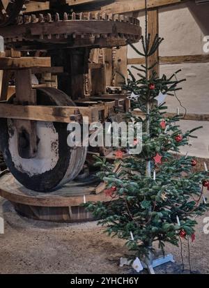 Innenraum der alten Wassermühle mit Weihnachtsbaum in Lage, Deutschland auf dem Anwesen Twickel, mit Ölmühlensteinen im Hintergrund. Stockfoto