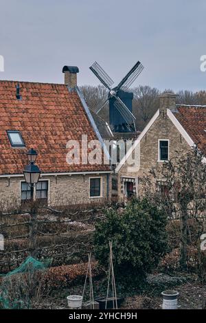 Blick auf zwei Häuser und die Windmühle der befestigten Stadt Bourtange während des sonntagsmarkts. Altes Mauerwerk und rote Dachziegel. Wintergarten in t Stockfoto