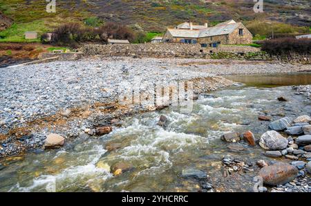 Der Fluss Crackington fließt über den Sand- und Kiesstrand in das Meer bei Crackington Haven an der Nordküste von Cornwall, England, Großbritannien. Stockfoto