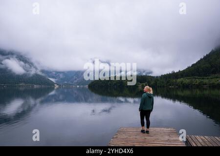 Frau, die am Hallstätter Seeufer steht und den Blick auf die bewölkten Berge genießt, Obertraun, Österreich Stockfoto