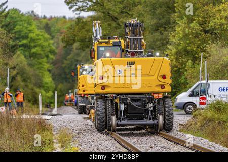 Mehrere gelbe Baumaschinen arbeiten auf einer Gleisbaustelle in grüner Umgebung, Gleisbau Hermann Hesse Bahn, Bezirk C Stockfoto