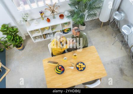 Panoramaaufnahme von oben in voller Länge eines romantischen kaukasischen Ehepaares, das Frühstück zu Hause genießt Stockfoto