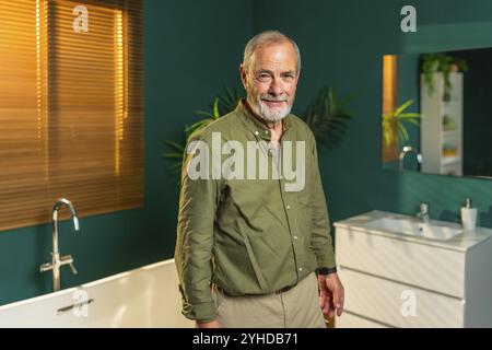 Porträt eines kaukasischen älteren Mannes, der zu Hause im Badezimmer steht und in die Kamera lächelt Stockfoto