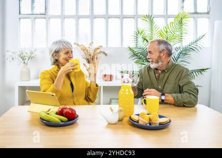Frontalansicht eines glücklichen kaukasischen, reiferen Paares, das während des gesunden Frühstücks zu Hause spricht Stockfoto