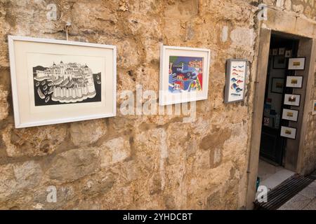 Souvenirladen für Touristen, in dem Souvenirs wie gerahmte Drucke an der Außenwand und in den Zimmern innerhalb der Stadtmauern der Altstadt von Dubrovnik, Kroatien, verkauft werden. (138) Stockfoto