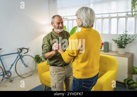 Dreiviertel Foto eines romantischen glücklichen Seniorenpaares, das zusammen im Wohnzimmer tanzt Stockfoto