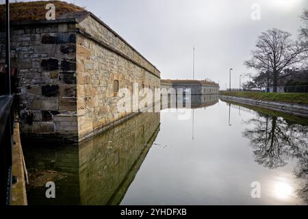 HAMPTON, Virginia – der historische Burggraben und die äußeren Befestigungen von Fort Monroe, Amerikas größtem Steinfort, tauchen durch den Morgennebel auf. Die atmosphärischen Bedingungen betonen die massiven Granitmauern und Verteidigungsmerkmale dieser Küstenbefestigung aus dem 19. Jahrhundert. Dieses erhaltene militärische Meisterwerk zeigt eine anspruchsvolle Küstenverteidigungsarchitektur. Stockfoto