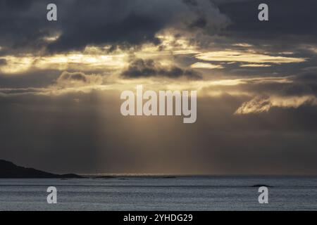 Sonnenstrahlen brechen durch dunkle Wolken über dem Norwegischen Meer. Abendlicht Stockfoto