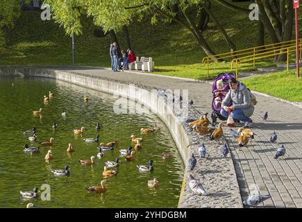 MOSKAU, RUSSLAND, 10. OKTOBER 2017: Eine Frau mit einem Baby füttert Enten auf dem Kaiteich. Der südwestliche Bezirk von Moskau (Vwesenski-Straße). Sonniges da Stockfoto