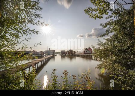 Holzhäuser im Wasser. Ferienort am See bei Sonnenuntergang. Lange Holzstege führen zu den einzelnen Häusern. Landschaftsaufnahme des schwimmenden V Stockfoto