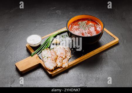 Traditionelle Borschtsch-Suppe mit Sauerrahm, grünen Zwiebeln, Knoblauch und Schweinefleisch an Bord Stockfoto