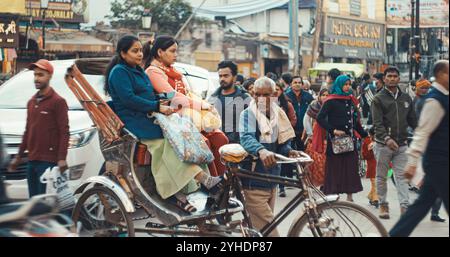 Varanasi, Uttar Pradesh, Indien. Der alte Rikscha-Trischa-Fahrer trägt weibliche Passagiere auf der Straße. Verkehr Auf Straßenmotorrädern, Rikscha Stockfoto