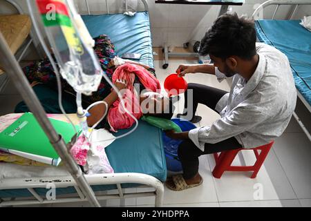 Dhaka, Bangladesch. November 2024. Ein Verwandter gießt Wasser auf den Kopf eines Dengue-Patienten, der an Dengue-Fieber leidet, ruhen Sie am 11. November 2024 im „Shaheed Suhrawardy“ Medical Colleague Hospital in Dhaka, Bangladesch. Seit dem 1. Januar 2024 bis zum 11. November 2024 sind insgesamt 75.142 Menschen von Dengue betroffen. Mindestens 310 Menschen sind bei Bangladeschs schlimmstem Dengue-Ausbruch aller Zeiten gestorben, sagten Beamte am 11. November, als überlastete Krankenhäuser kämpfen, Tausende von Patienten zu behandeln. Quelle: Mamunur Rashid/Alamy Live News Stockfoto