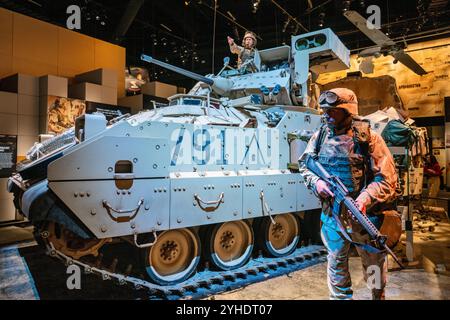 Bradley-Kampffahrzeug-Nationalmuseum US-Army Fort Belvoir Virginia | FORT BELVOIR, Virginia — Eine Schaufensterpuppen-Soldatin steht neben einem M2A3 Bradley-Kampffahrzeug in einem Wüstendiorama im Nationalmuseum der US-Armee, markiert mit "/91" für den Einsatz des Fahrzeugs im Golfkrieg. Die 25-mm-Kettenkanone und die Panzerung des Bradleys verdeutlichen die Rolle des Typs bei der Bodenoffensive des Golfkriegs 1991. Hintergrundkarten von Irak und Afghanistan verbinden die Ausstellung mit späteren Operationen im Nahen Osten. Stockfoto