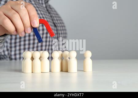 Mann mit Magnet, der hölzerne menschliche Figuren am Lichttisch anzieht, Nahaufnahme Stockfoto