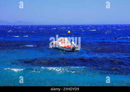 Kleines Motorboot, das in der Nähe des Ufers in rauer See vor Anker liegt, Insel Tilos, griechische Inseln Dodekanes, Griechenland, Europa Stockfoto