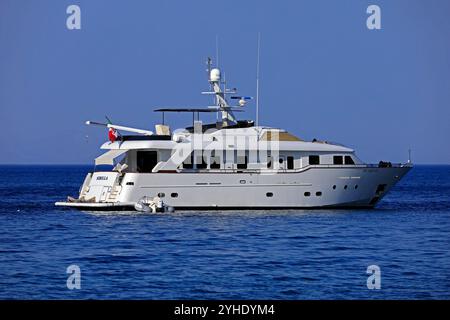 Luxusmotoryacht (Sibilla) und Sonnenbadefrau auf dem Vorderdeck vor Anker vor der Insel Tilos, den griechischen Inseln Dodekanes, Griechenland, Europa Stockfoto