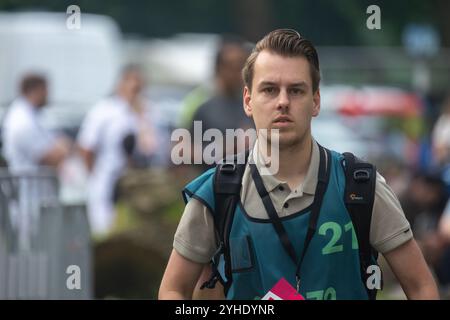 Utrecht, Region Utrecht, Niederlande - 19.05.2024: Ein junger Pressefotograf mit blauer Weste und rotem „Press“-Abzeichen geht, während er seine Wri überprüft Stockfoto