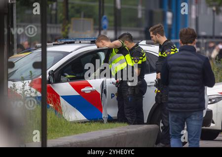 Utrecht, Region Utrecht, Niederlande - 19.05.2024: Drei Polizeibeamte stehen an einem markierten Polizeifahrzeug, einer in die offene Tür gelehnt. Sie tragen h Stockfoto