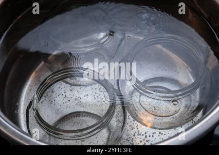 Drei Glasdosen, die in kochendem Wasser sterilisiert werden. Konservierungspräparate. Stockfoto