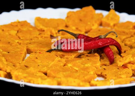 Sehr Nahaufnahme Von Gujarati Kathiyawadi Scharfe Dhokali Sabji Auf Weißer Platte, Rote Chillies Auf Der Oberseite, Isoliert Auf Schwarzem Hintergrund, Selektiver Fokus Stockfoto