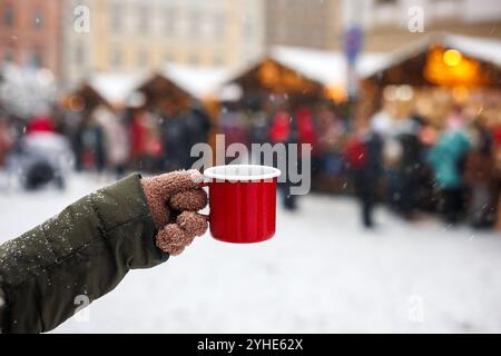 Frau genießt Glühwein oder Punsch in einem roten Becher auf dem traditionellen Weihnachtsmarkt Stockfoto