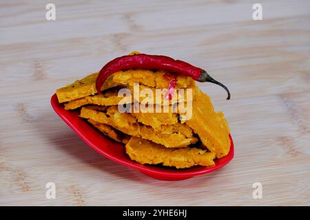 Blick von oben auf Gujarati Kathiyawadi scharfe Dhokali Sabji mit einem roten Chili auf einer Schüssel. Die atemberaubende schwarze Kulisse unterstreicht das rote Gericht Stockfoto