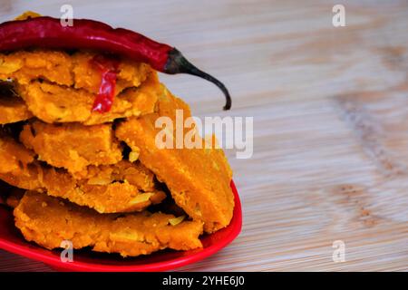 Blick von oben auf Gujarati Kathiyawadi scharfe Dhokali Sabji mit einem roten Chili auf einer Schüssel. Die atemberaubende schwarze Kulisse unterstreicht das rote Gericht Stockfoto