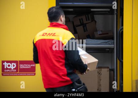 Berlin, Deutschland. November 2024. Ein DHL-Mitarbeiter trägt ein Paket in einen Lieferwagen. Quelle: Hannes P. Albert/dpa/Alamy Live News Stockfoto