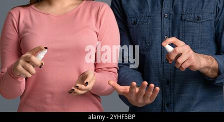 Vorsichtsmaßnahmen Während Des Ausbruch Des Coronavirus. Junges Paar Anwendung Desinfektionsmittel Spray auf die Hände Stockfoto
