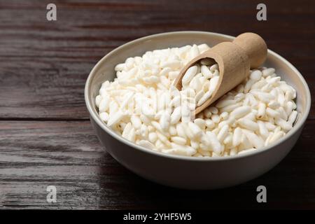 Puffreis in Schüssel und Schaufel auf Holztisch, Nahaufnahme Stockfoto